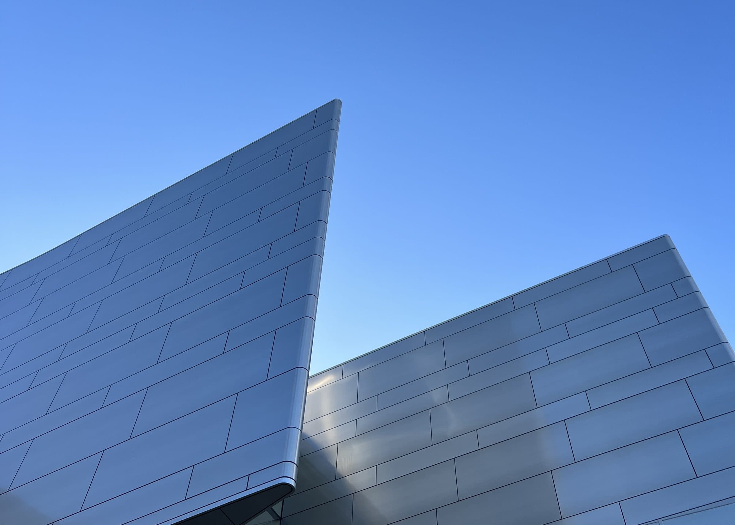 Metal-clad building facade against a clear blue sky